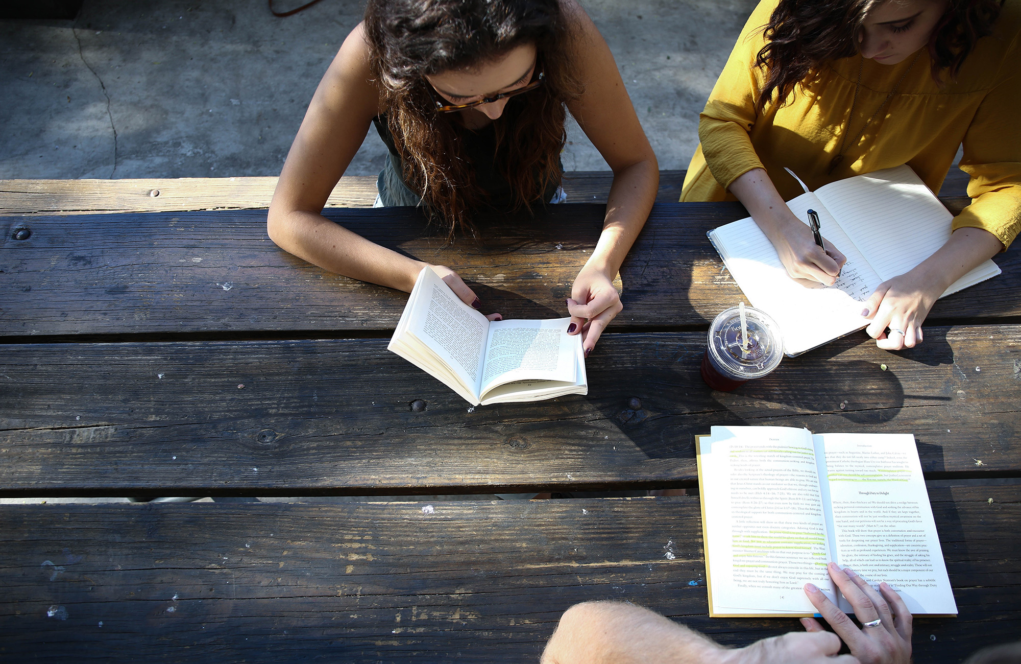Image of two young women and a young man at a table with books writing notes - KILROY