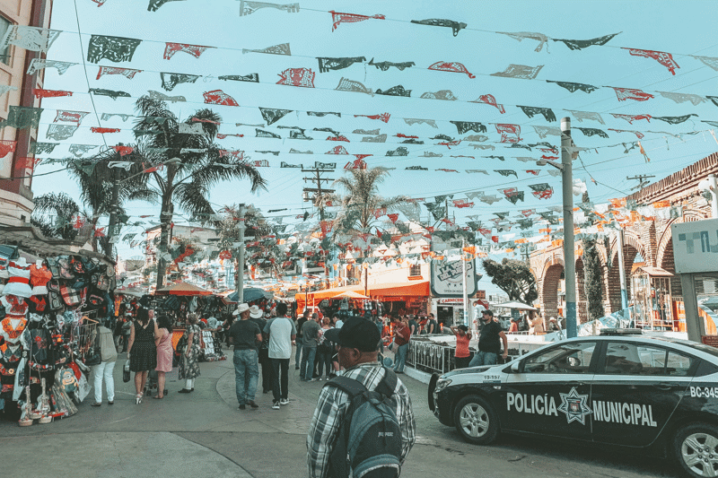 Busy street with a lot of people and a police car in Baja California in Mexico