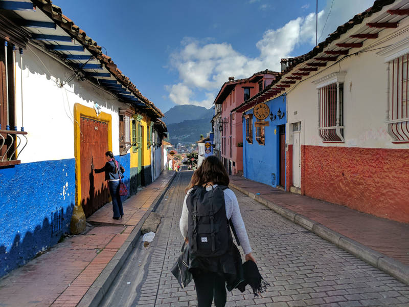 Image of a female backpacker walking down a traditional colonial street in South America - KILROY