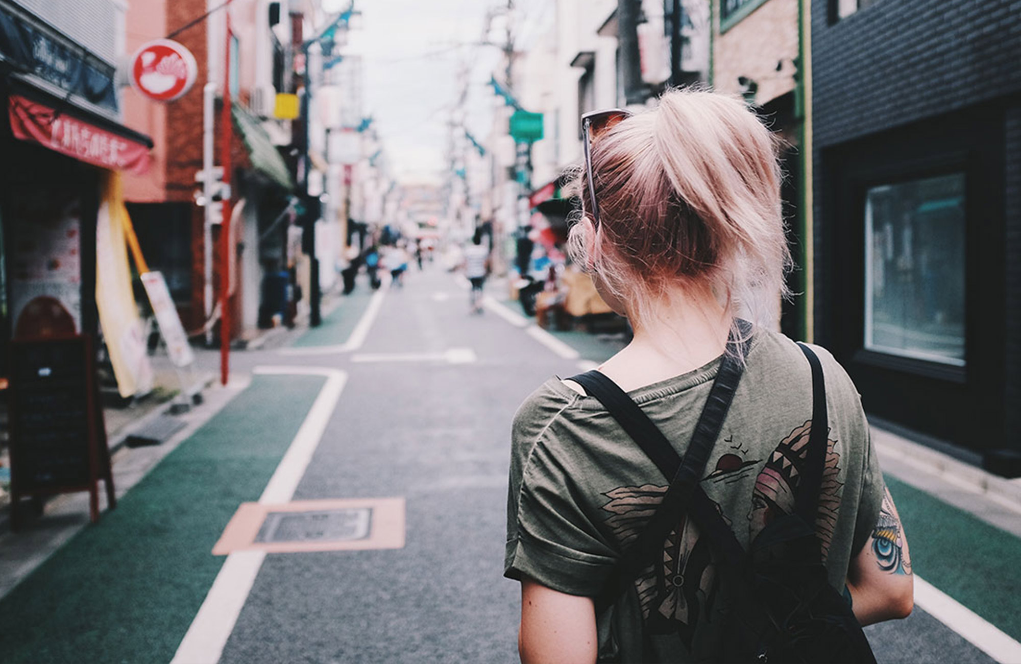 Image of a solo female traveller walking down a street in Asia - KILROY