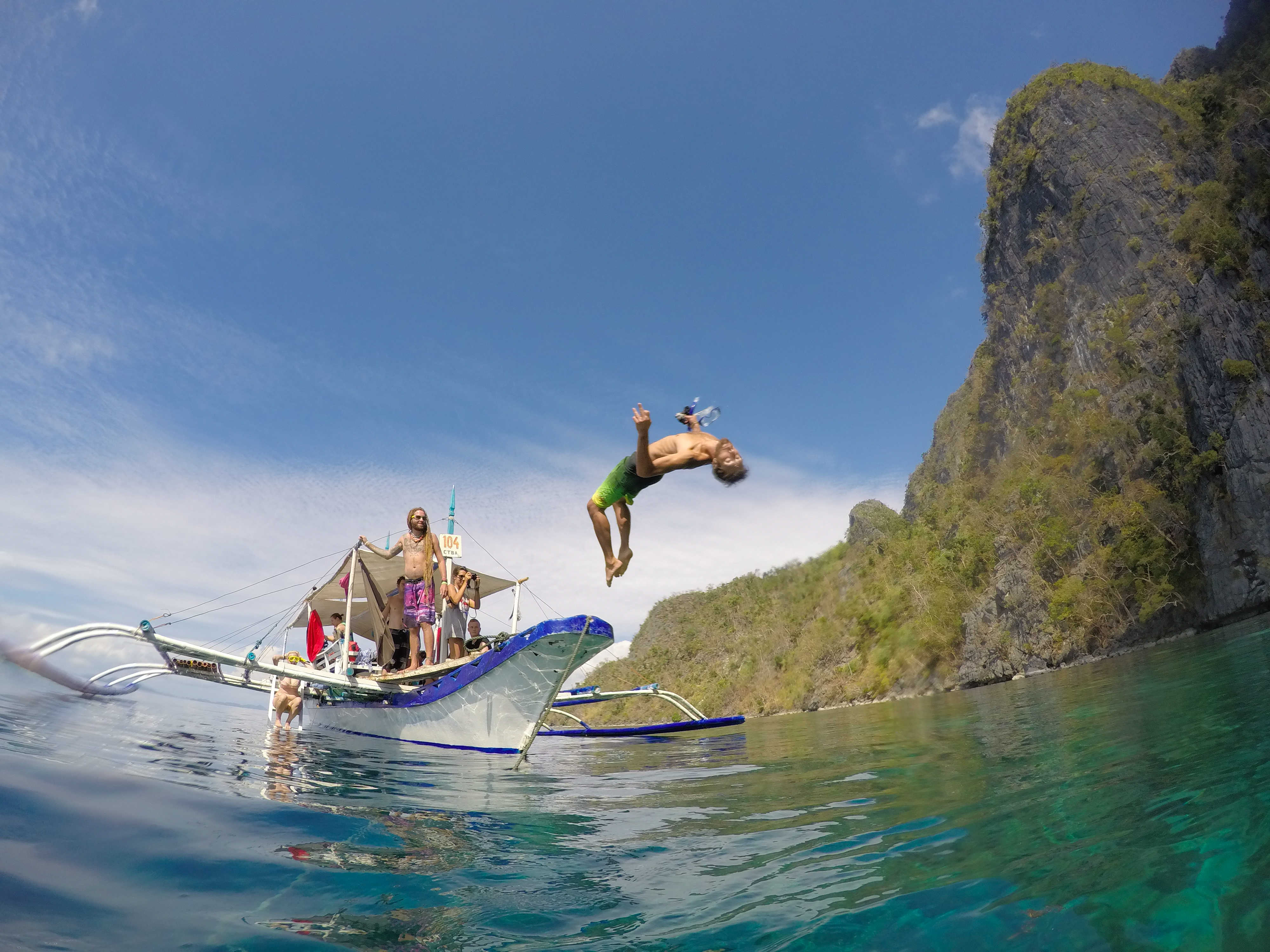 Image of a man jumping off a sailing boat in the Philippines - KILROY