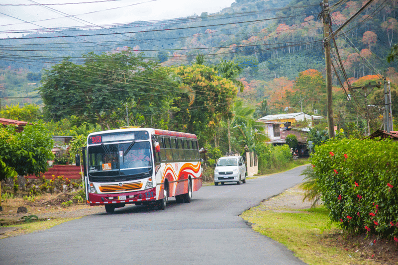 Red and white bus driving on a countryside road in Costa Rica