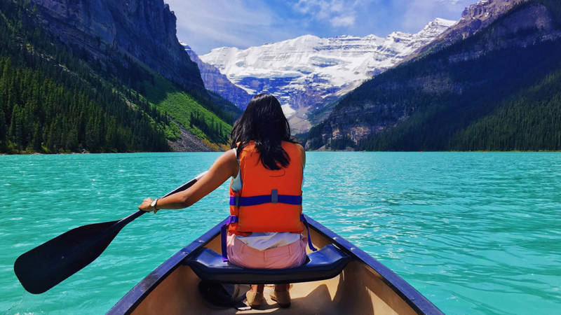 Image of a woman kayaking on a lake at Banff National Park in Canada - KILROY