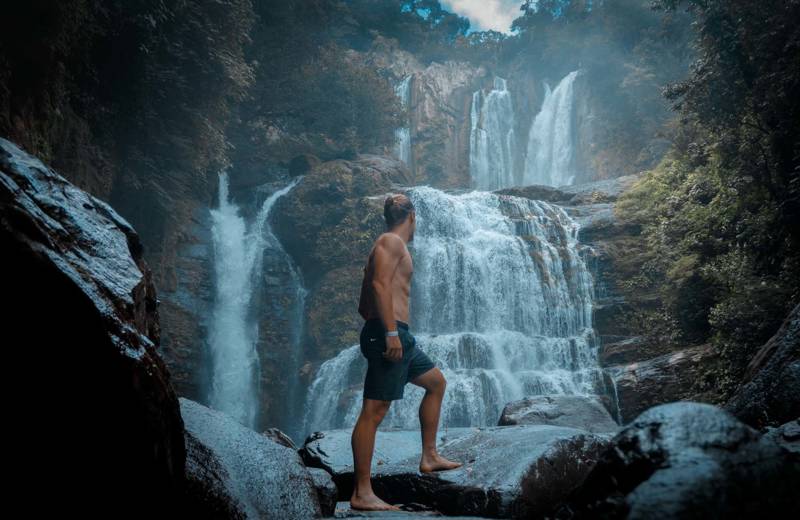 Guy standing in front of a big waterfall in Costa Rica