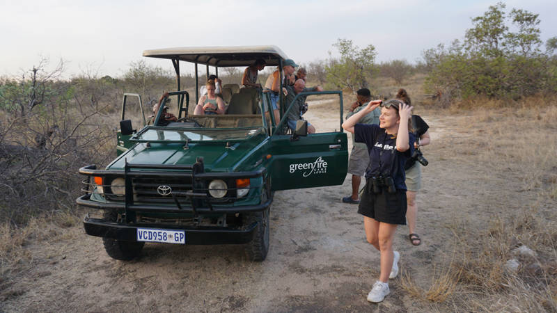 Image of a a group of travellers beside a safari jeep in South Africa - KILROY