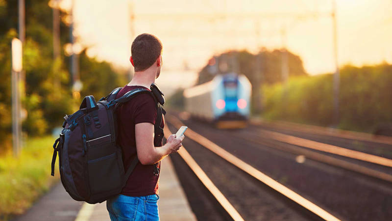 Image of a man waiting for a train on a platform in Europe - KILROY